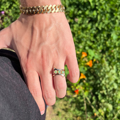 A yellow gold bypass shank ring mounted with three round cabochon cut Ethiopian fire opals.