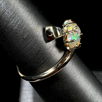 A yellow gold bypass shank ring mounted with three round cabochon cut Ethiopian fire opals.