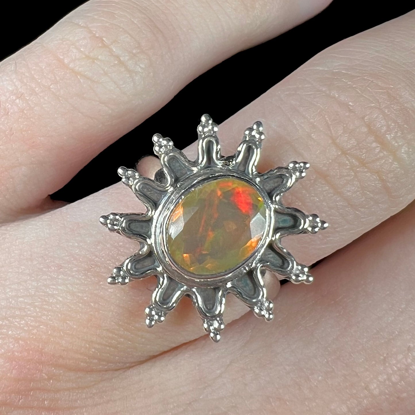 A sterling silver sunburst-style ring mounted with a faceted oval cut Ethiopian fire opal.