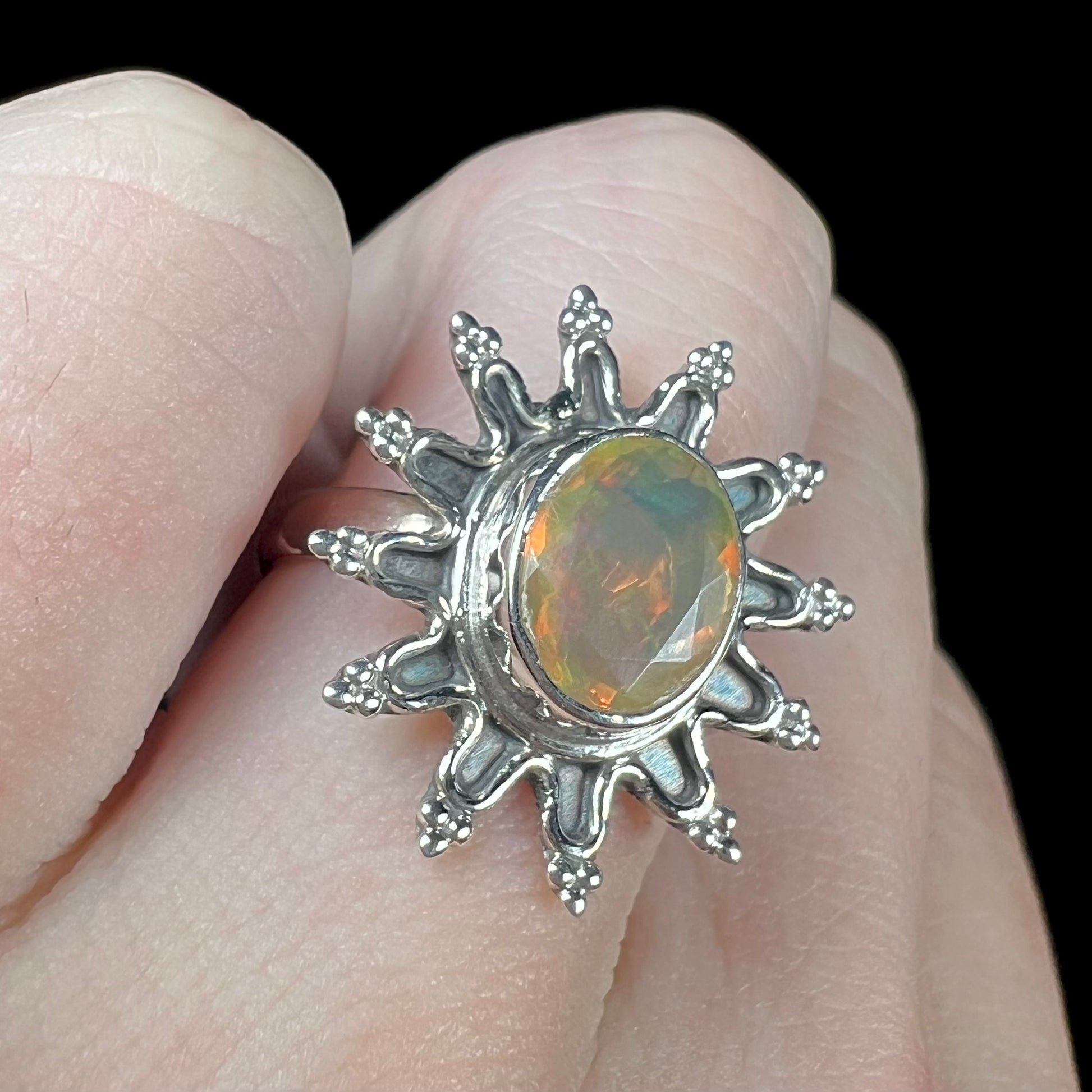 A sterling silver sunburst-style ring mounted with a faceted oval cut Ethiopian fire opal.