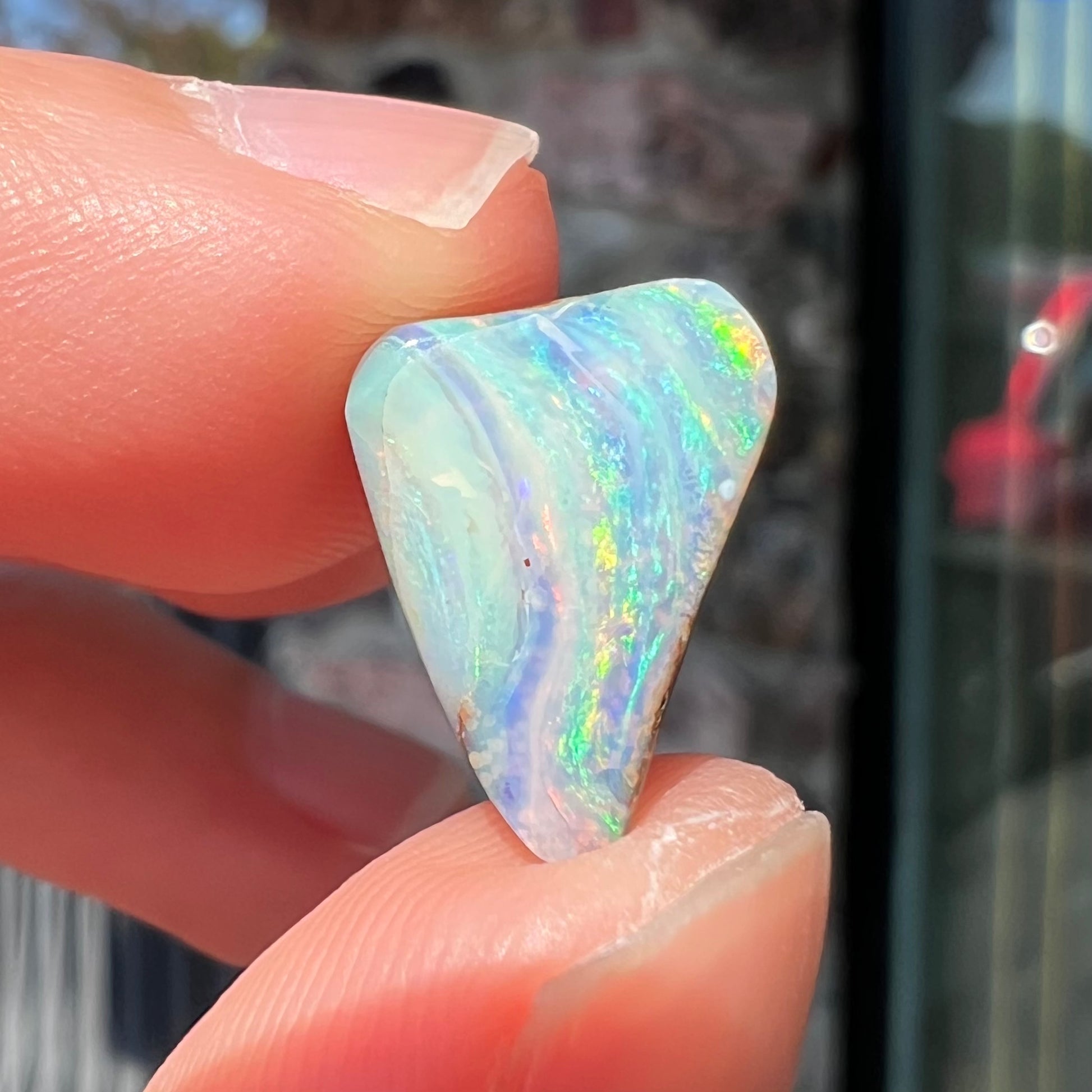 A loose, freeform boulder opal stone from Quilpie, Australia.  The opal has a fissure inclusion.