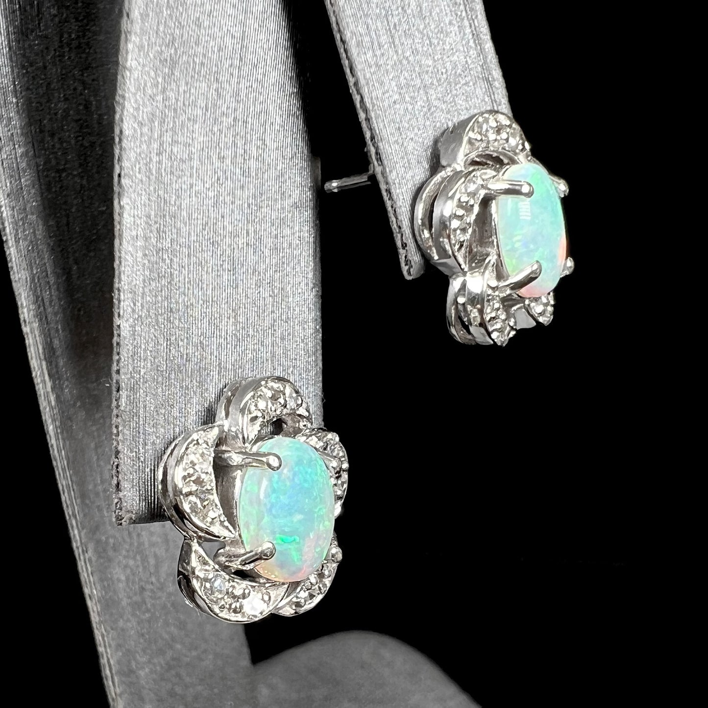 A pair of white gold flower stud earrings with diamonds mounted in the petals and opals set in the center.