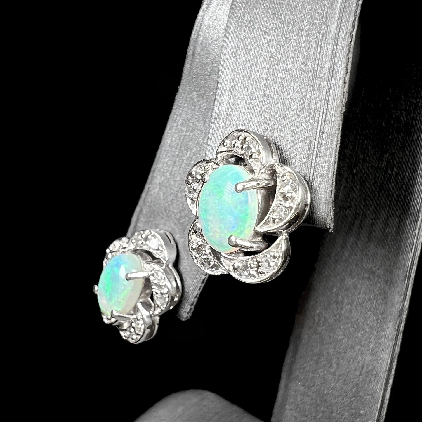 A pair of white gold flower stud earrings with diamonds mounted in the petals and opals set in the center.