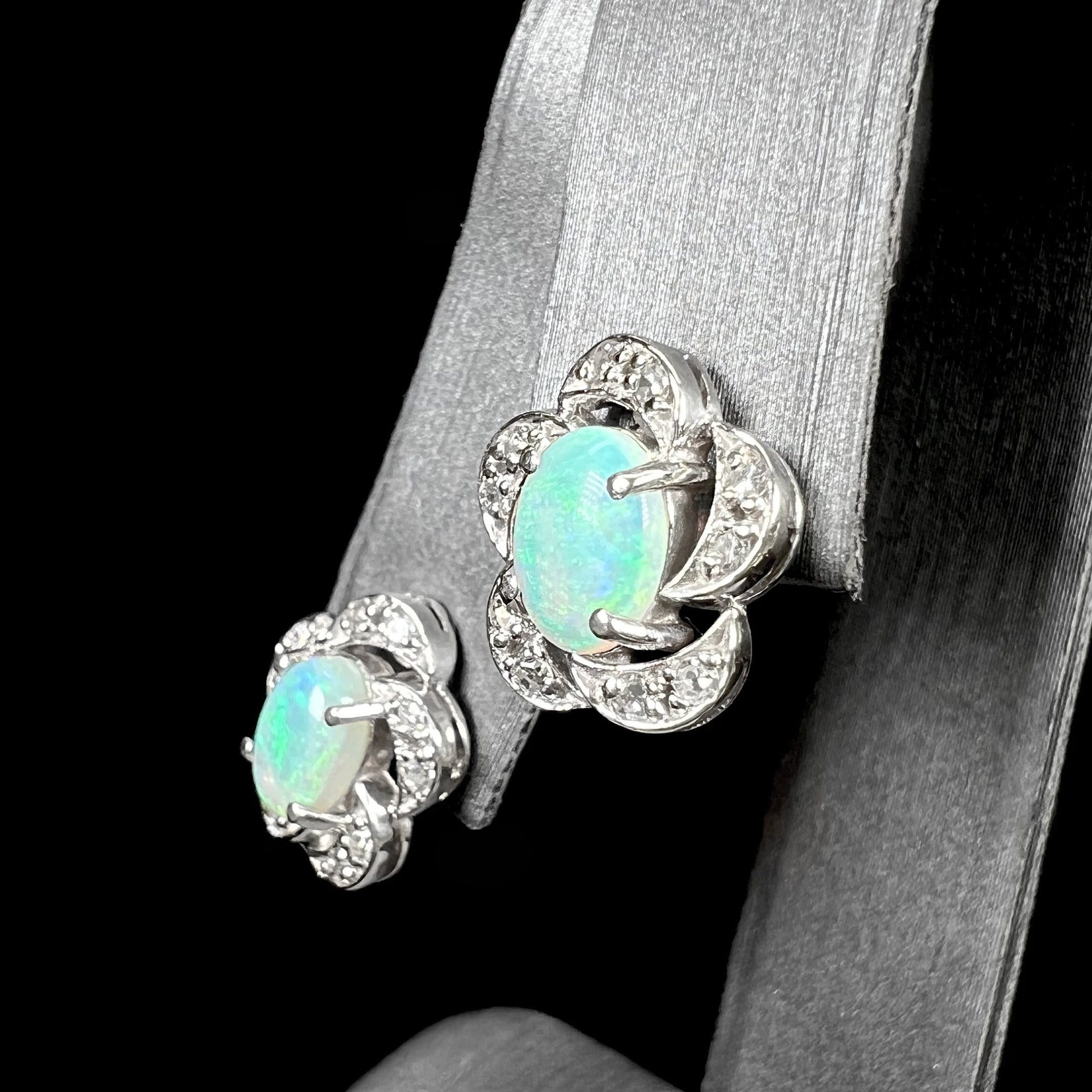 A pair of white gold flower stud earrings with diamonds mounted in the petals and opals set in the center.