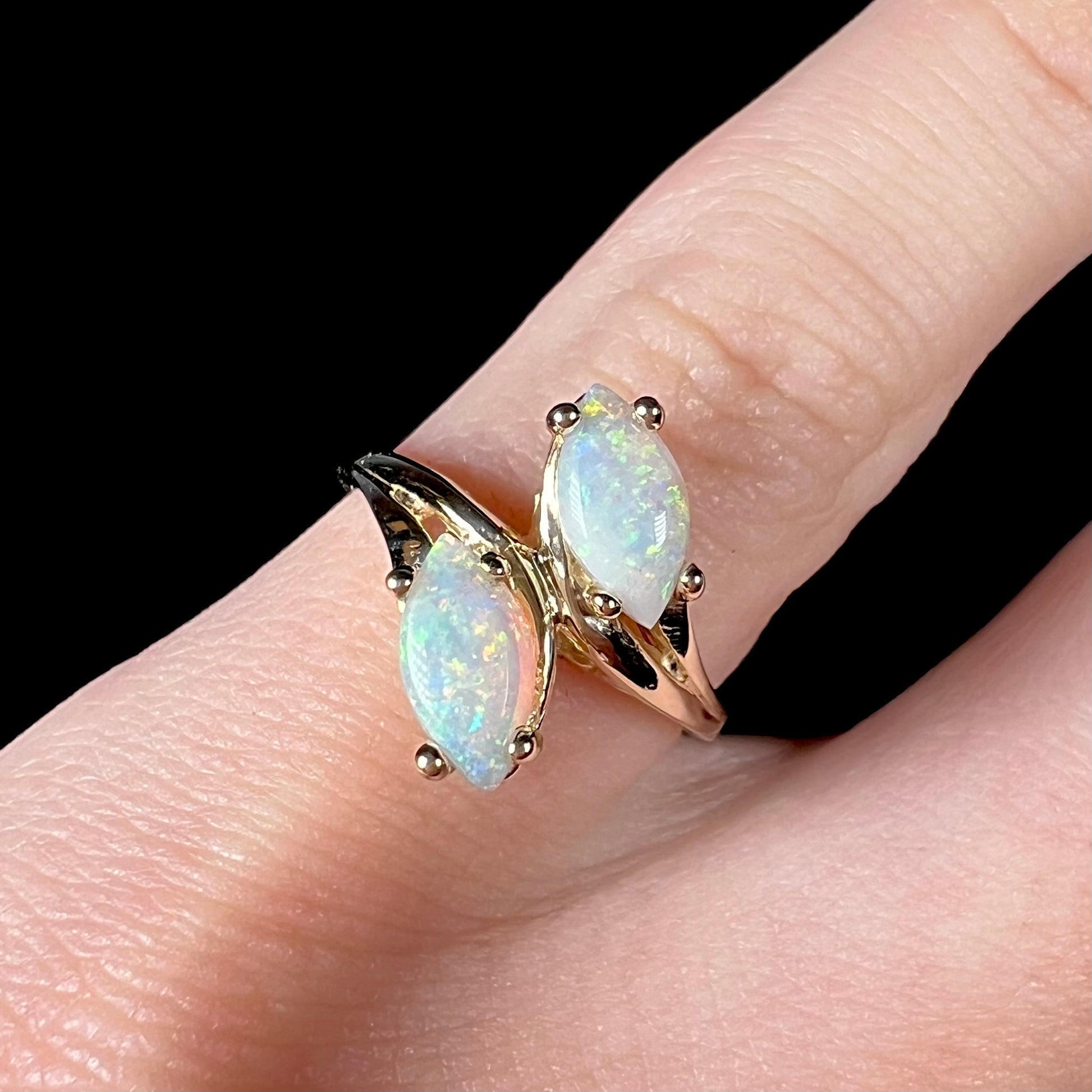 A yellow gold ring mounted with two prong-set marquise cut opal cabochons.