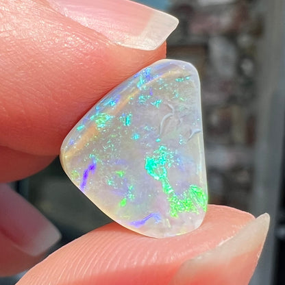 A freeform shaped blue-green light opal stone from Lightning Ridge, Australia.