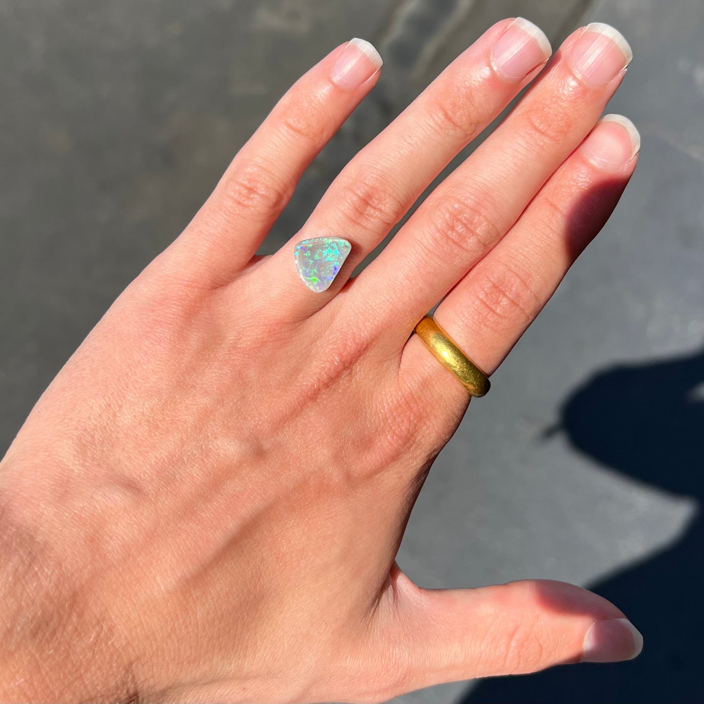 A freeform shaped blue-green light opal stone from Lightning Ridge, Australia.