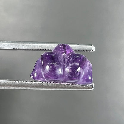 A stone frog carved from purple amethyst crystal.