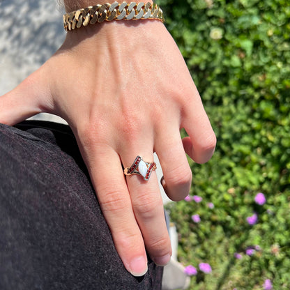 A marquise cut white opal ring.  The ring is accented with channel set reddish orange garnets.