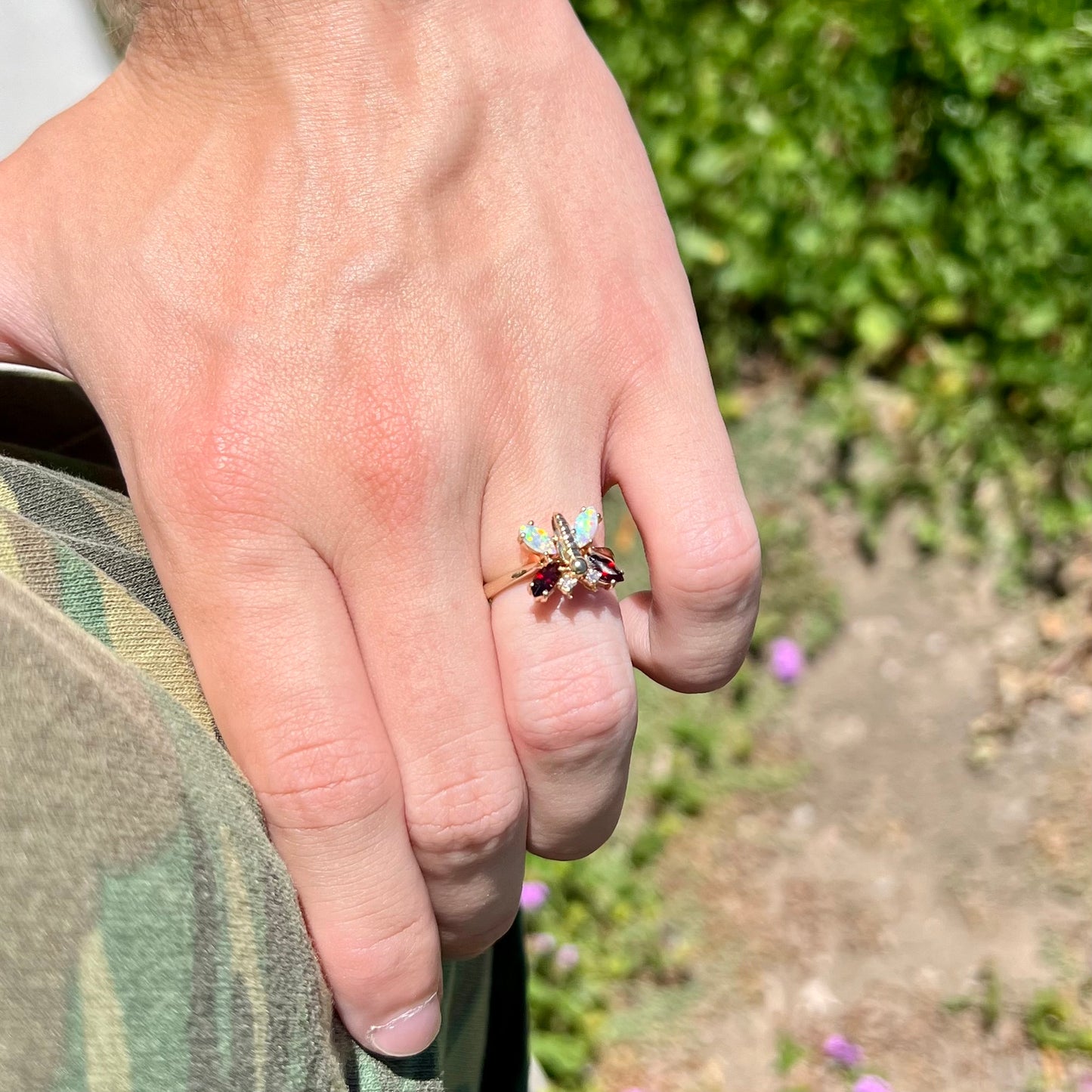 A yellow gold butterfly ring mounted with marquise cut garnets and opals and round diamond accents.