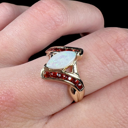 A marquise cut white opal ring.  The ring is accented with channel set reddish orange garnets.