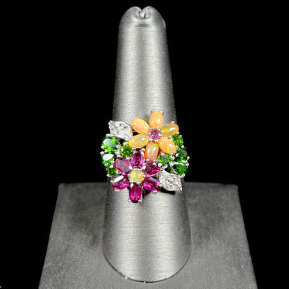 A ladies' gemstone flower design cluster ring set with Ethiopian fire opals, chrome diopsides, rhodolite garnets, and white topaz stones.