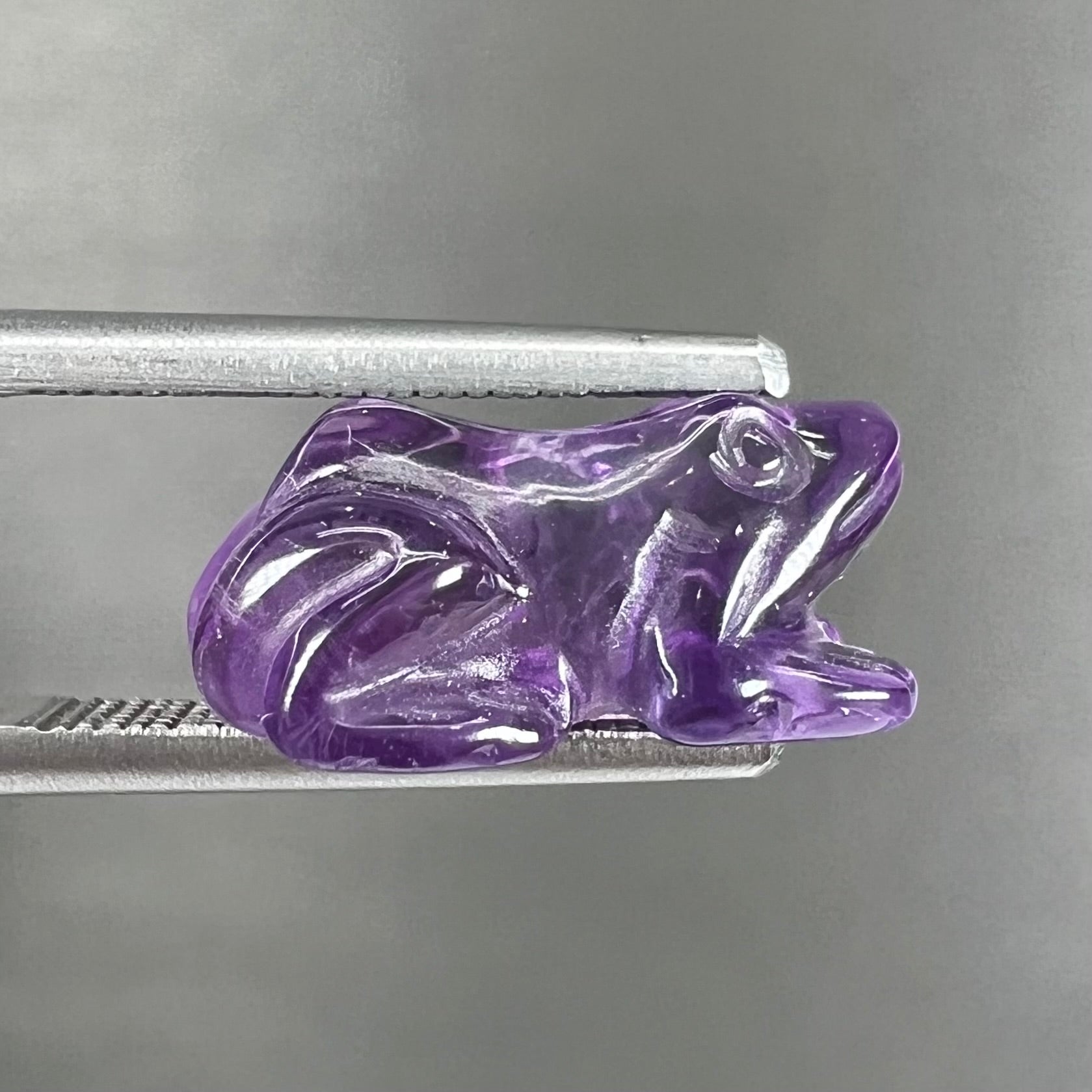 A stone frog carved from purple amethyst crystal.