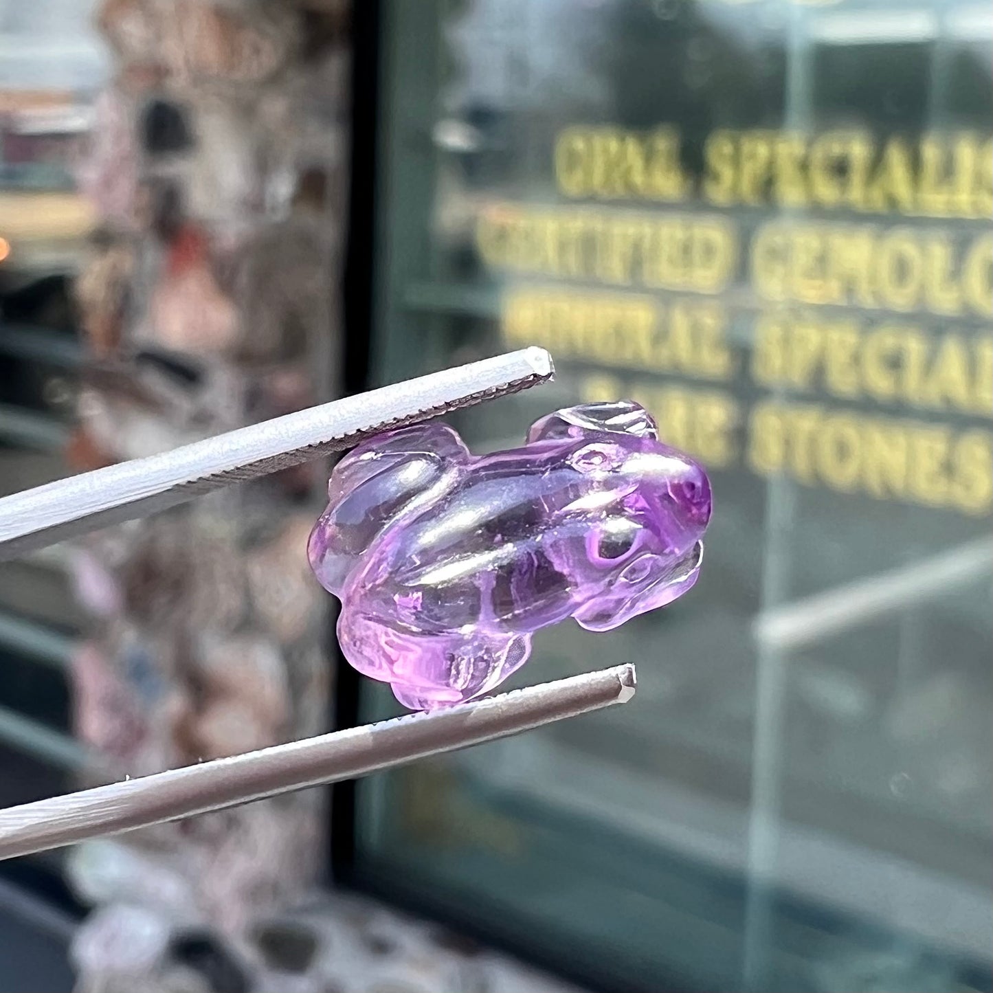 A stone frog carved from purple amethyst crystal.