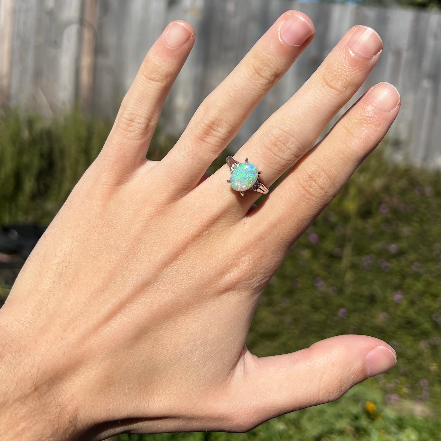 A platinum filigree opal engagement ring set with diamond accents.  The opal has green-blue colors.