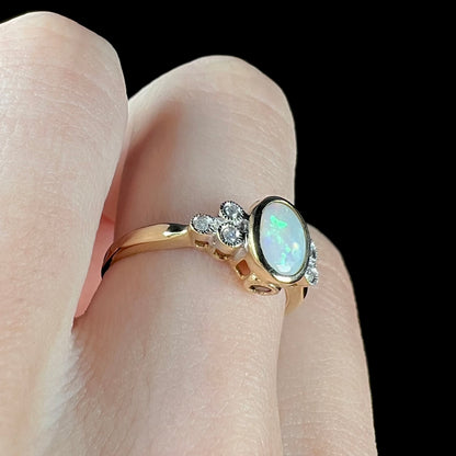 A ladies' yellow gold opal ring.  Three diamonds are set on each side of the opal.  Two rubies are set under the opal.