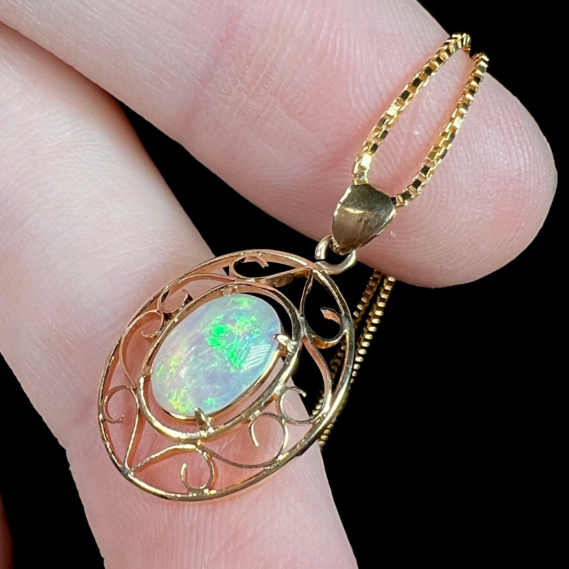 An 18 karat yellow gold filigree opal necklace.  The opal has bright green color play.