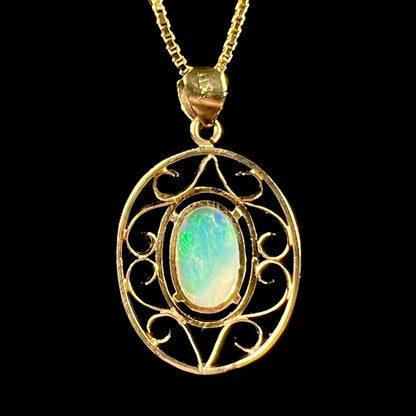 An 18 karat yellow gold filigree opal necklace.  The opal has bright green color play.