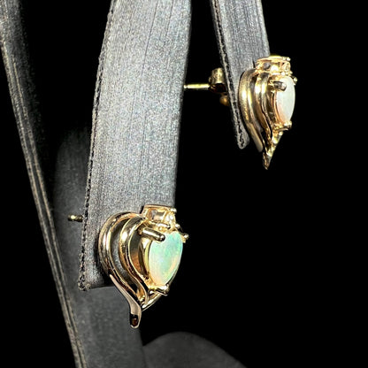 A pair of heart shaped, yellow gold opal stud earrings.  The top of the earrings have a diamond accent.