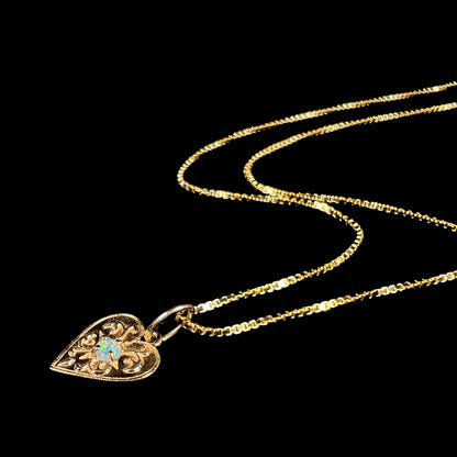 A yellow gold filigree heart necklace set with a round Australian crystal opal.  The opal has green fire.