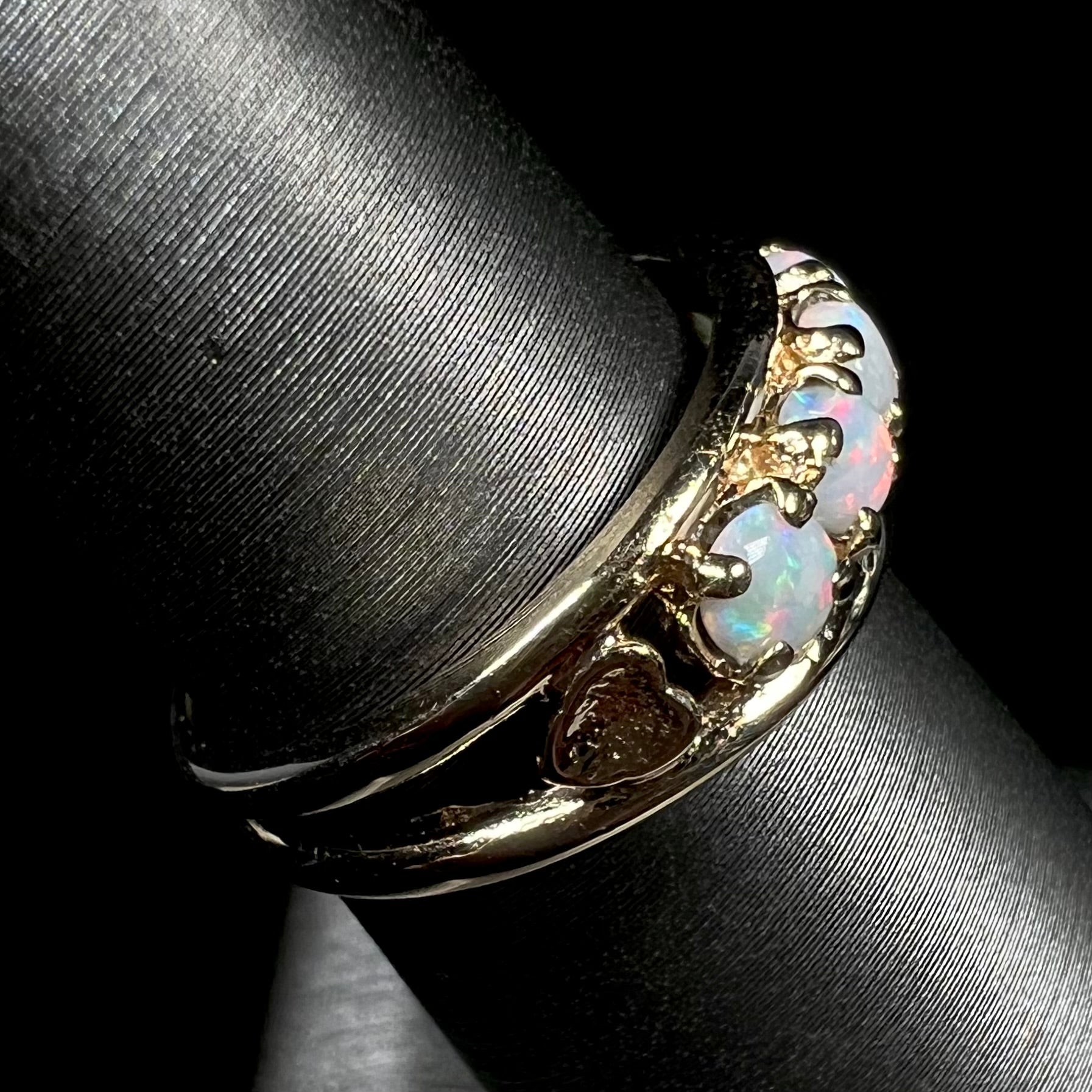 A yellow gold band set with five round cabochon cut opals and heart design accents.