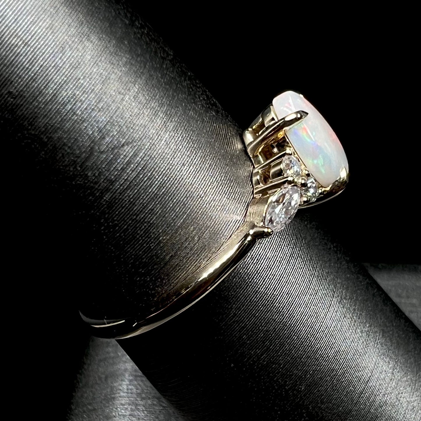 A dainty, pear shaped opal ring mounted in yellow gold with moissanite accents.