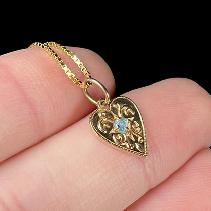 A yellow gold filigree heart necklace set with a round Australian crystal opal.  The opal has green fire.