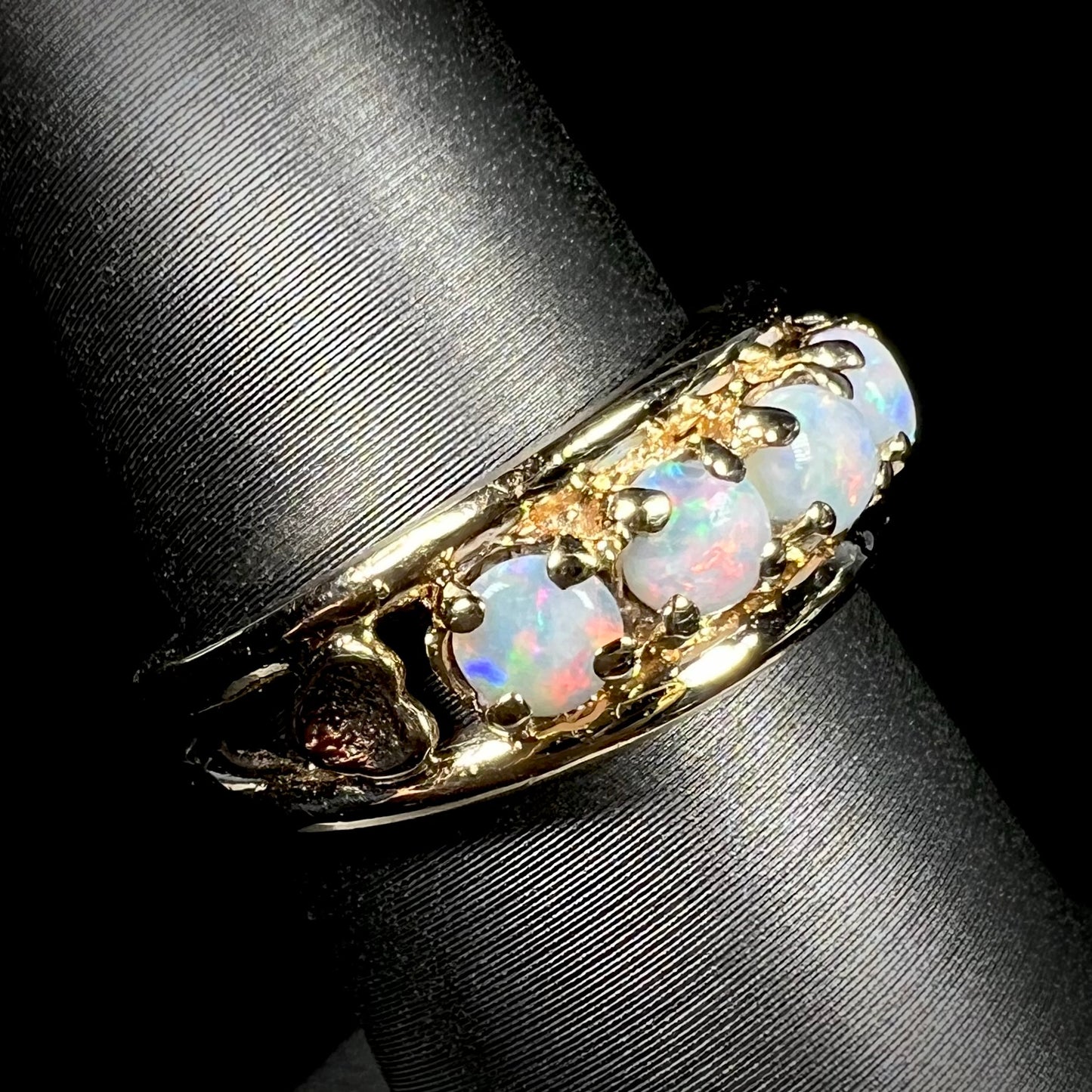 A yellow gold band set with five round cabochon cut opals and heart design accents.