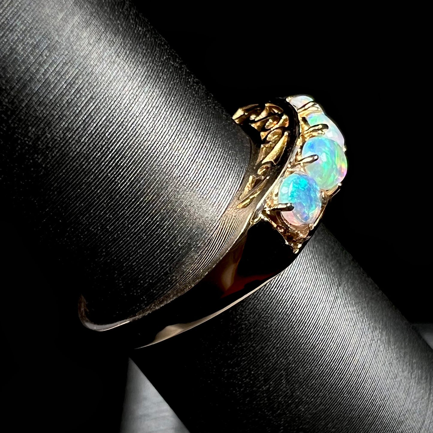 An 18 karat yellow gold line-style filigree ring mounted with five round, cabochon cut Australian crystal opals.