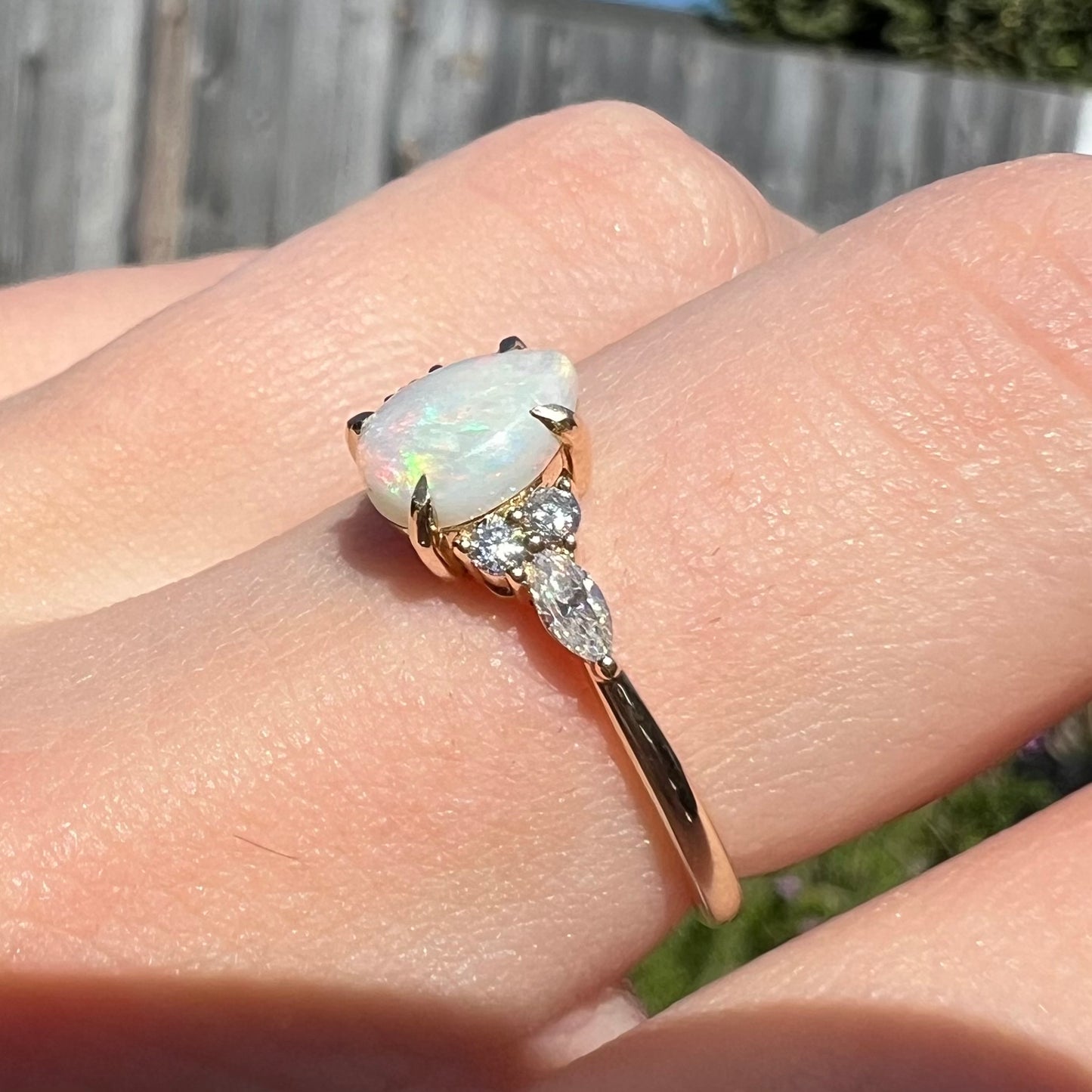 A dainty, pear shaped opal ring mounted in yellow gold with moissanite accents.