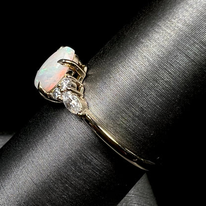 A dainty, pear shaped opal ring mounted in yellow gold with moissanite accents.