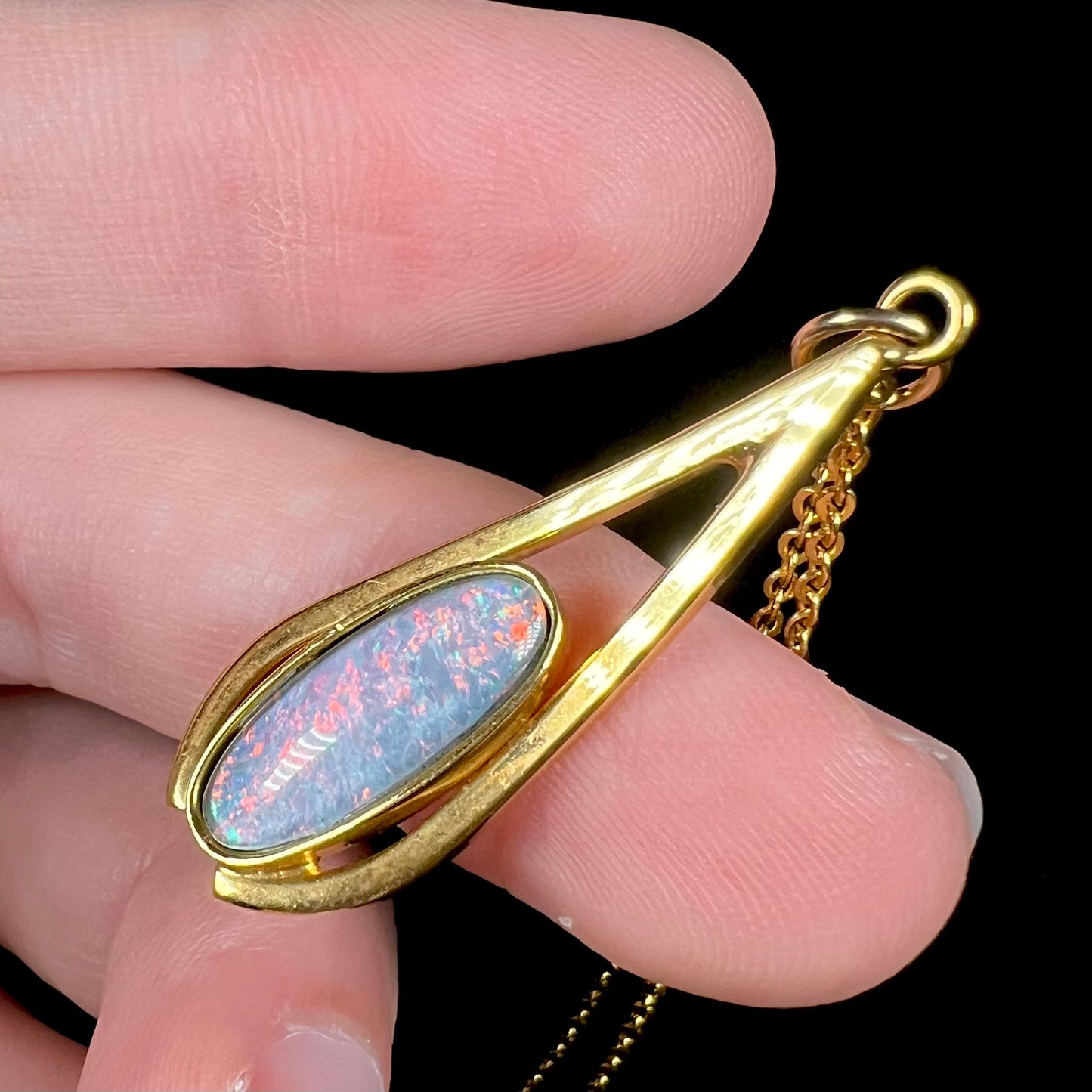 A yellow gold plated necklace set with an oval cut opal triplet.