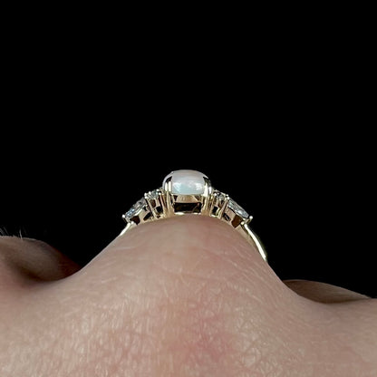 A dainty, pear shaped opal ring mounted in yellow gold with moissanite accents.