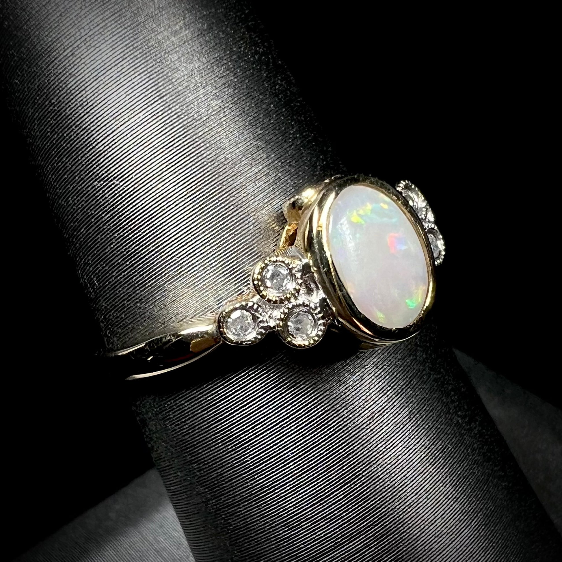 A ladies' yellow gold opal ring.  Three diamonds are set on each side of the opal.  Two rubies are set under the opal.