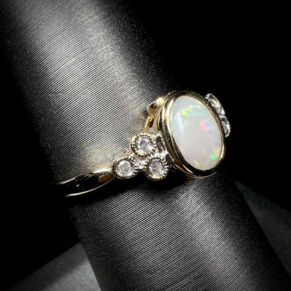 A ladies' yellow gold opal ring.  Three diamonds are set on each side of the opal.  Two rubies are set under the opal.