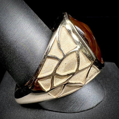 A men's heavy yellow gold ring mounted with a Mexican fire agate stone.  The shank of the ring is textured.