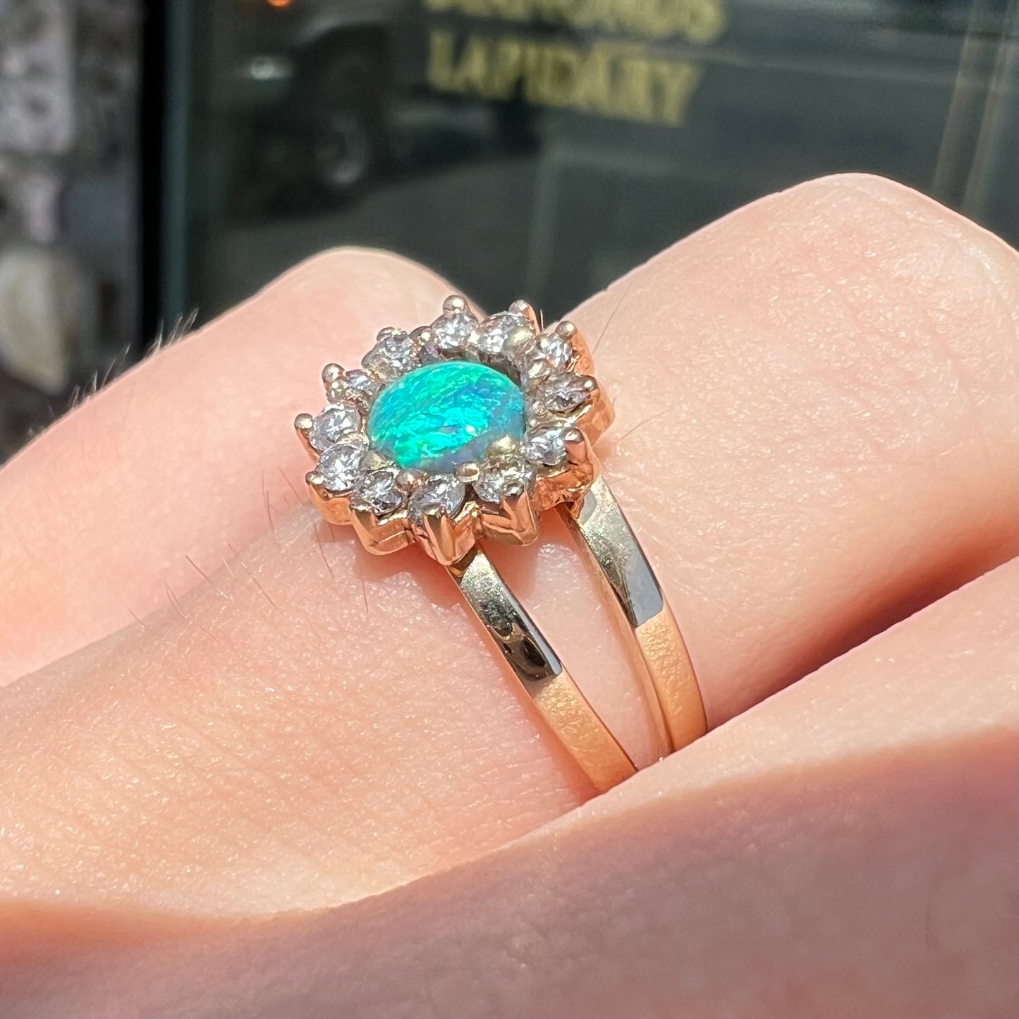 A ladies' round cut black opal and diamond halo ring.  The ring is yellow gold and has a split shank.