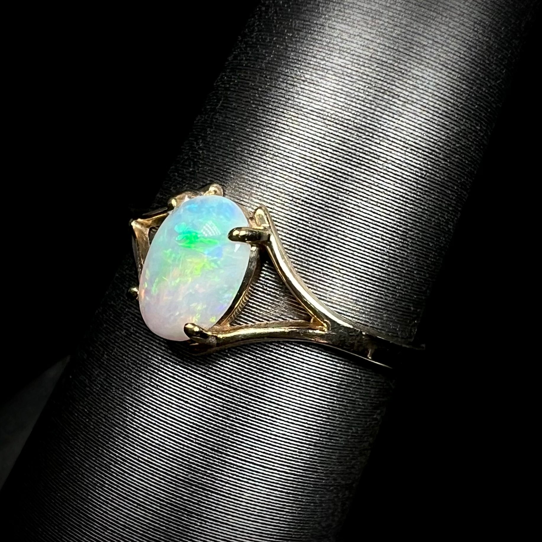 A ladies' simple opal solitaire ring.  The ring is yellow gold with a split shank.