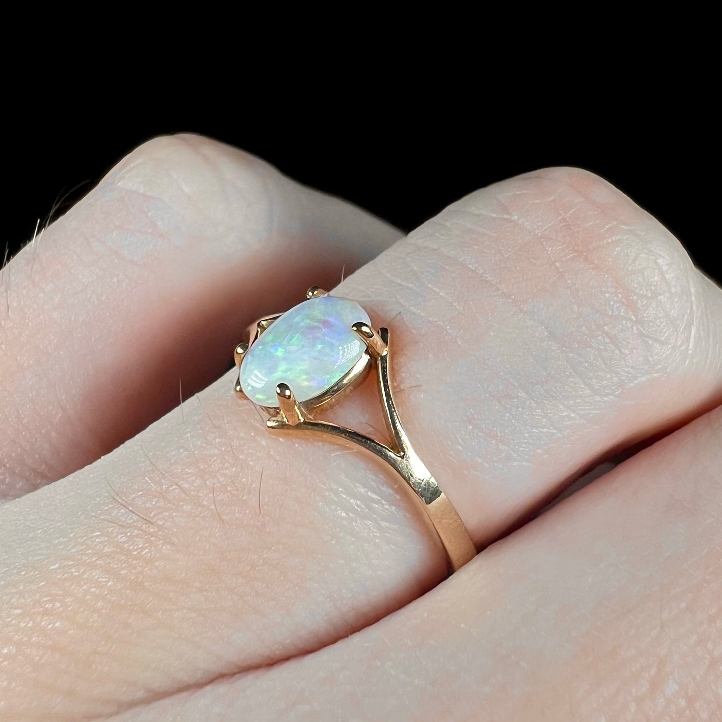 A ladies' simple opal solitaire ring.  The ring is yellow gold with a split shank.