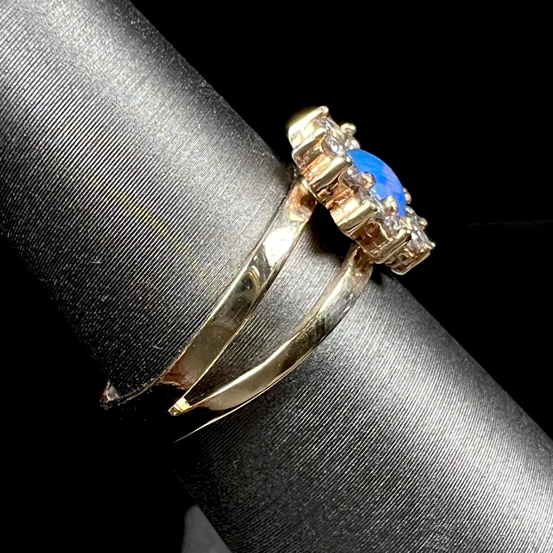 A ladies' round cut black opal and diamond halo ring.  The ring is yellow gold and has a split shank.