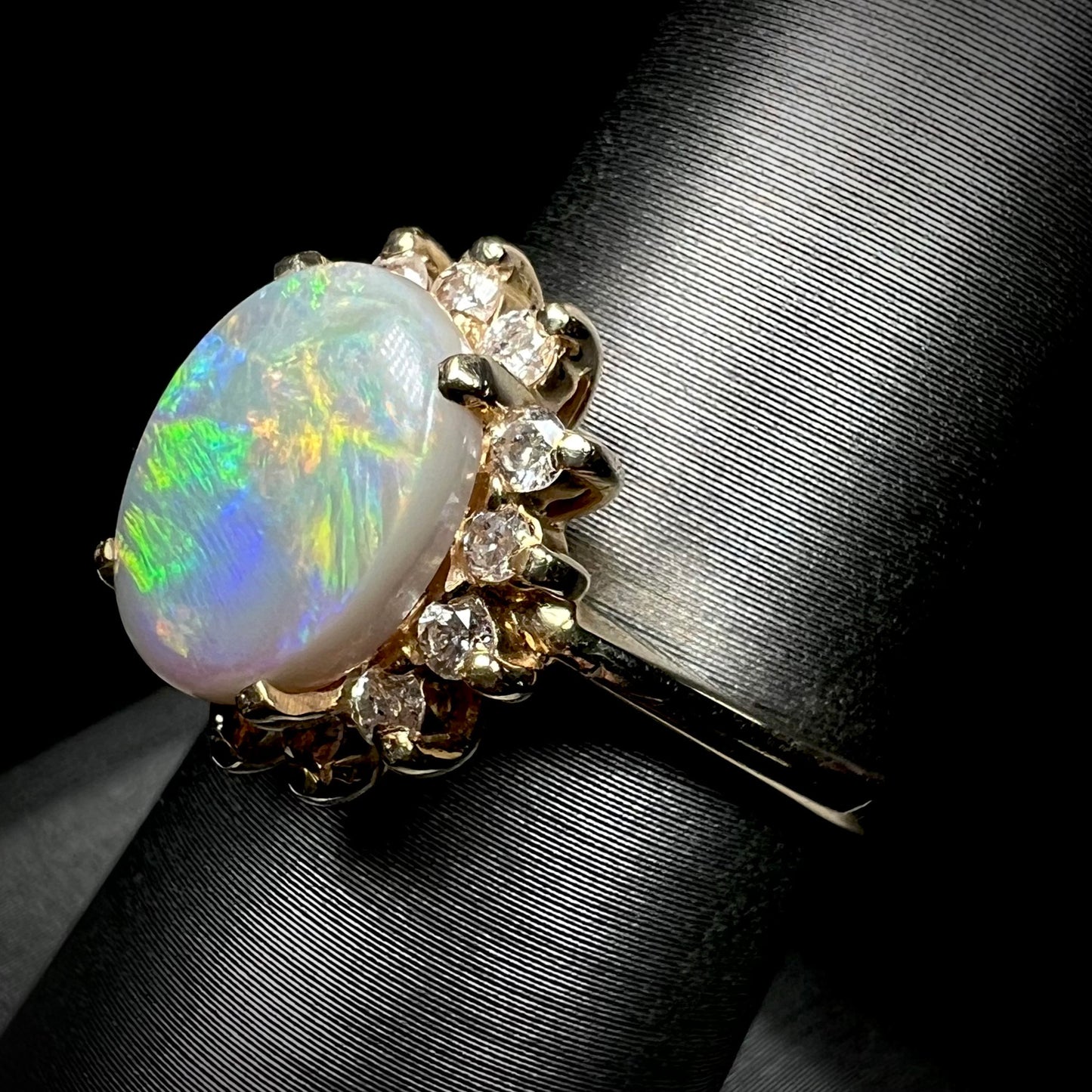 A yellow gold ring mounted with a Lightning Ridge semi-black opal.  The opal is surrounded by round diamonds.