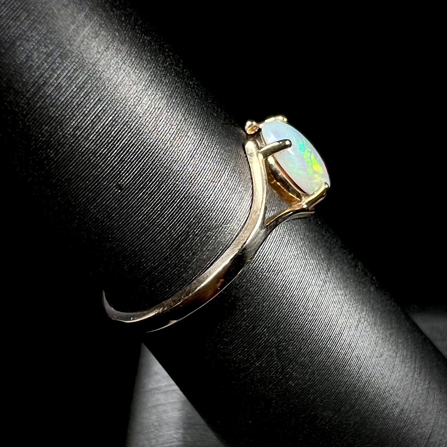 A ladies' simple opal solitaire ring.  The ring is yellow gold with a split shank.