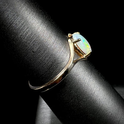 A ladies' simple opal solitaire ring.  The ring is yellow gold with a split shank.