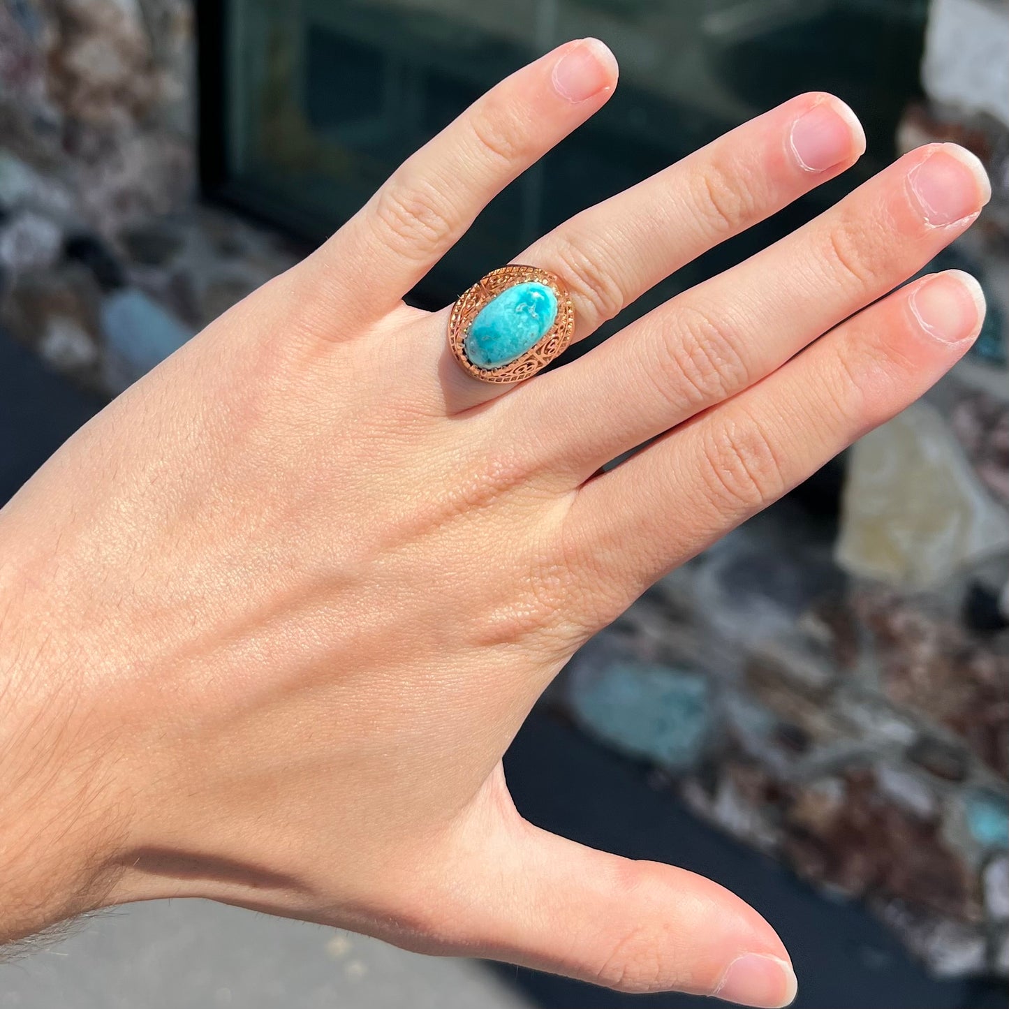 A yellow gold filigree style ring mounted with an oval Pilot Mountain turquoise stone.