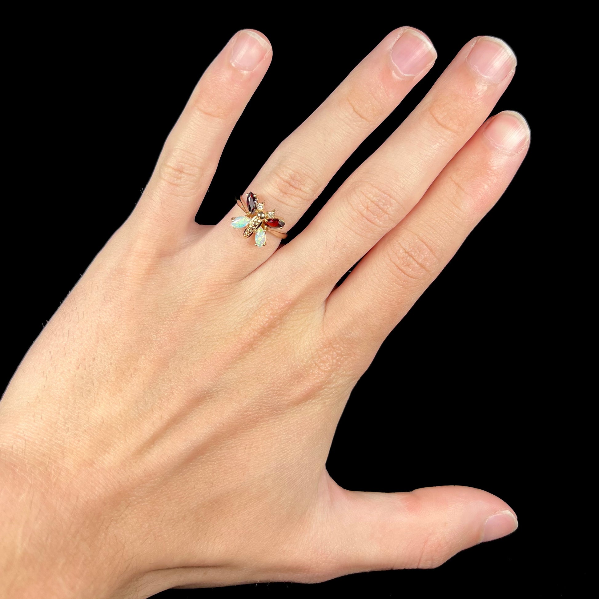 A yellow gold butterfly ring mounted with marquise cut garnets and opals and round diamond accents.