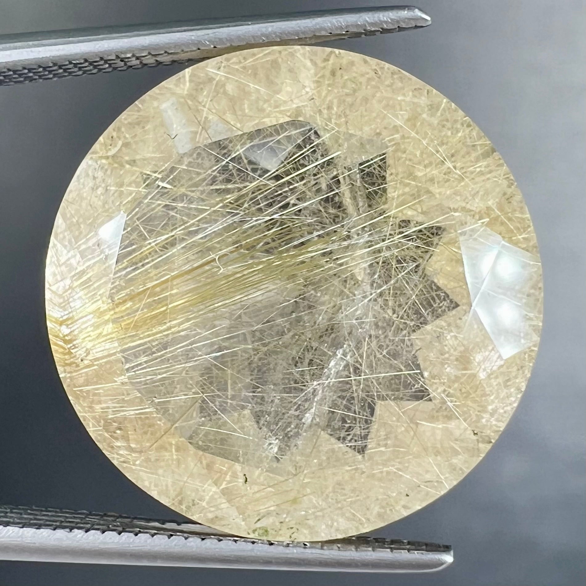 A loose, modified Early American round cut rutilated quartz gemstone.  The rutile inclusions are a golden color.