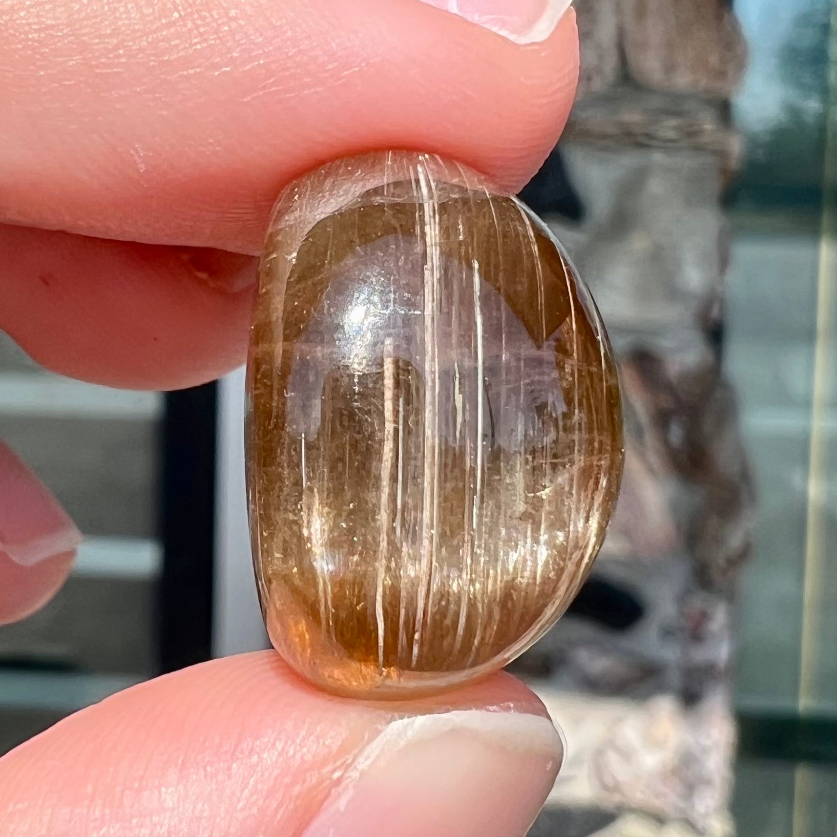 A loose, golden brown cat's eye dravite tourmaline gemstone.  The stone is cut into an oval shaped cabochon.