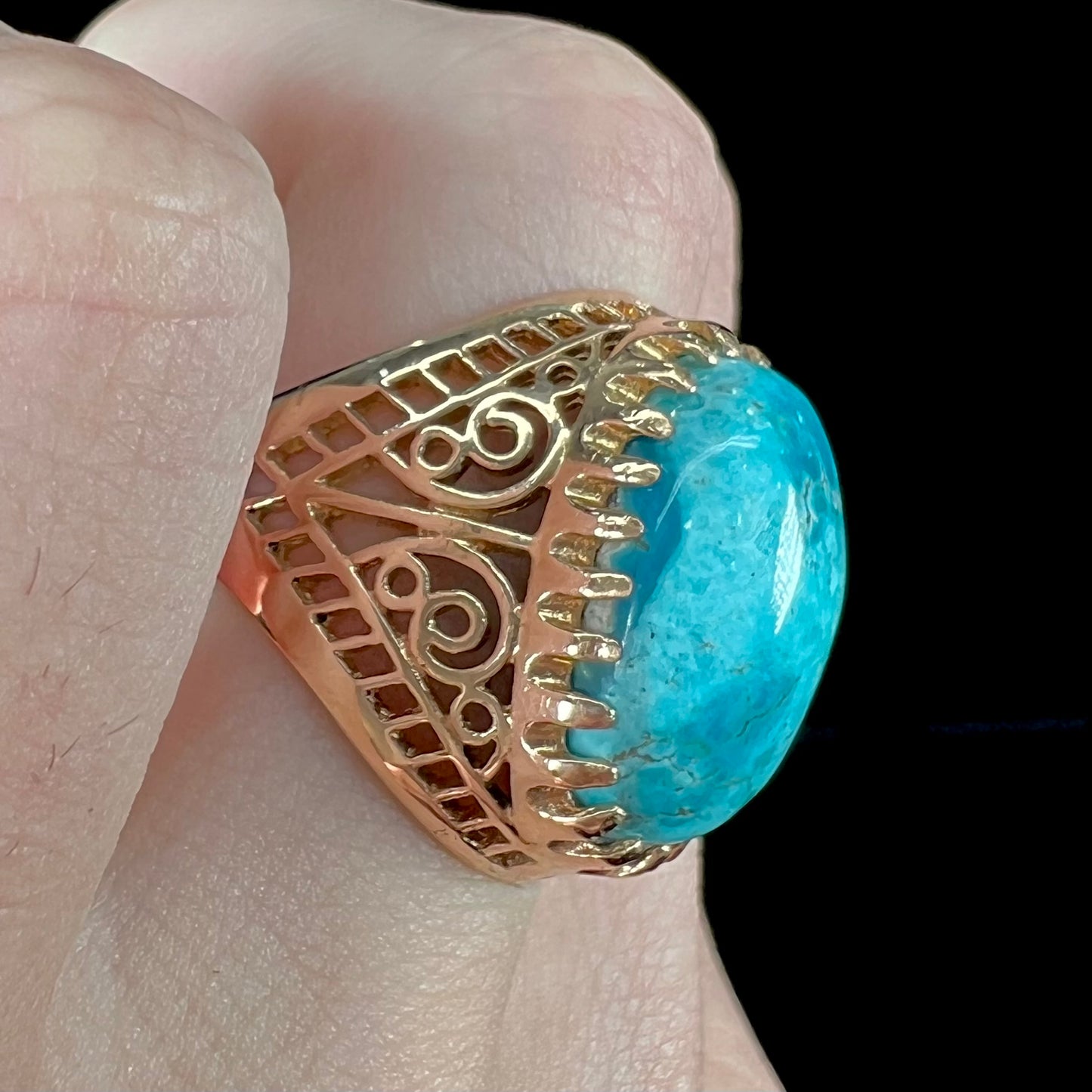 A yellow gold filigree style ring mounted with an oval Pilot Mountain turquoise stone.