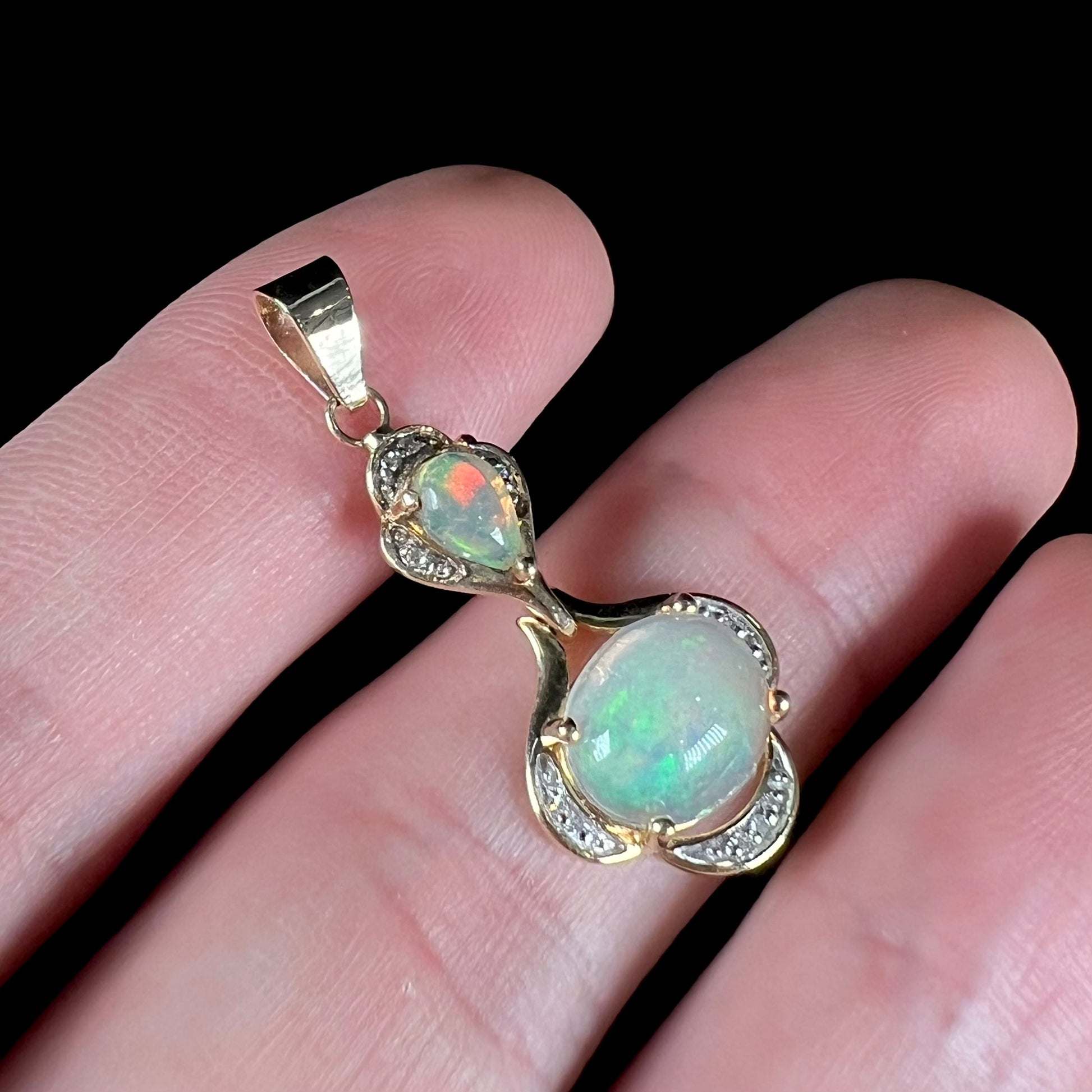 A ladies' yellow gold and diamond accented pendant set with two natural Ethiopian fire opals.