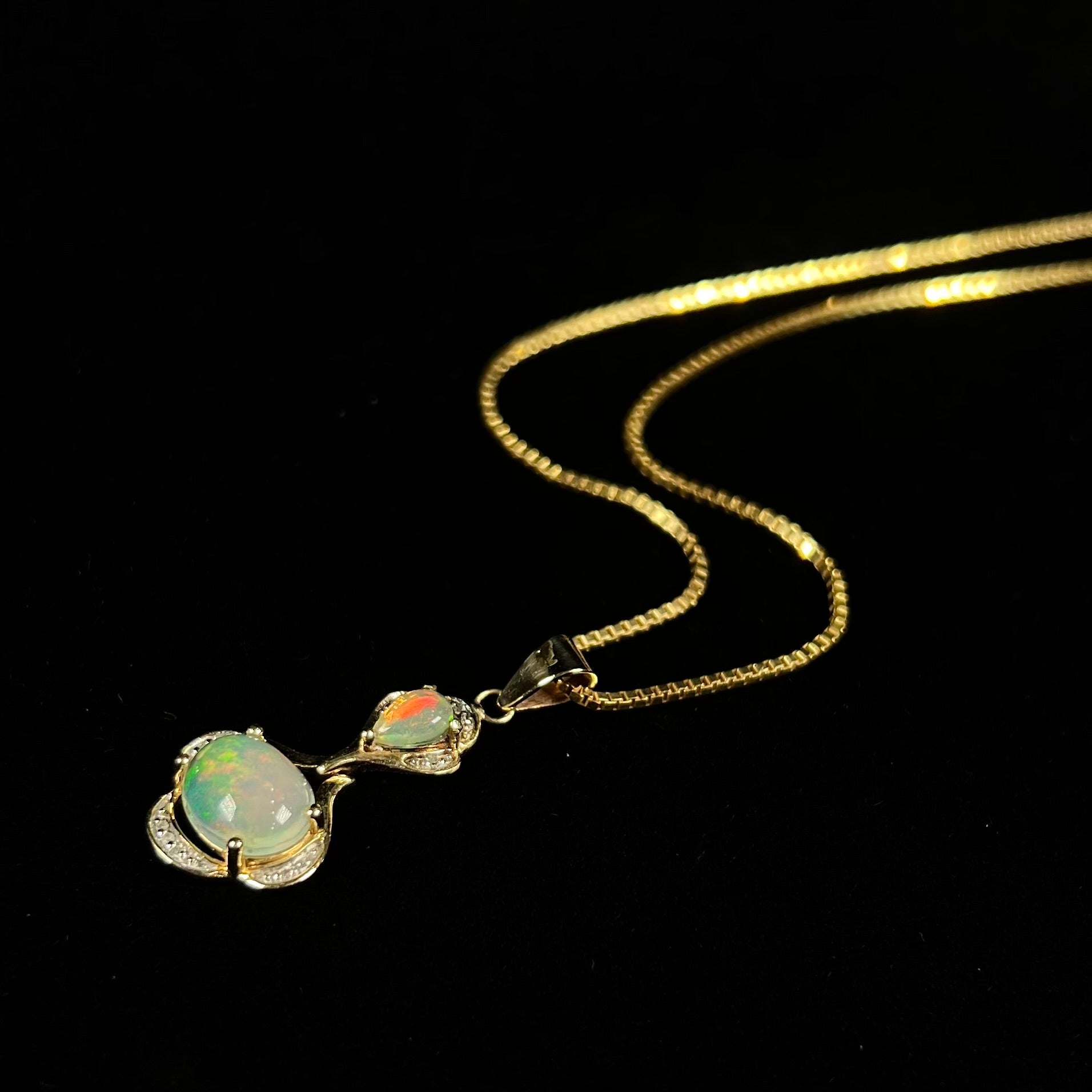 A ladies' yellow gold and diamond accented pendant set with two natural Ethiopian fire opals.